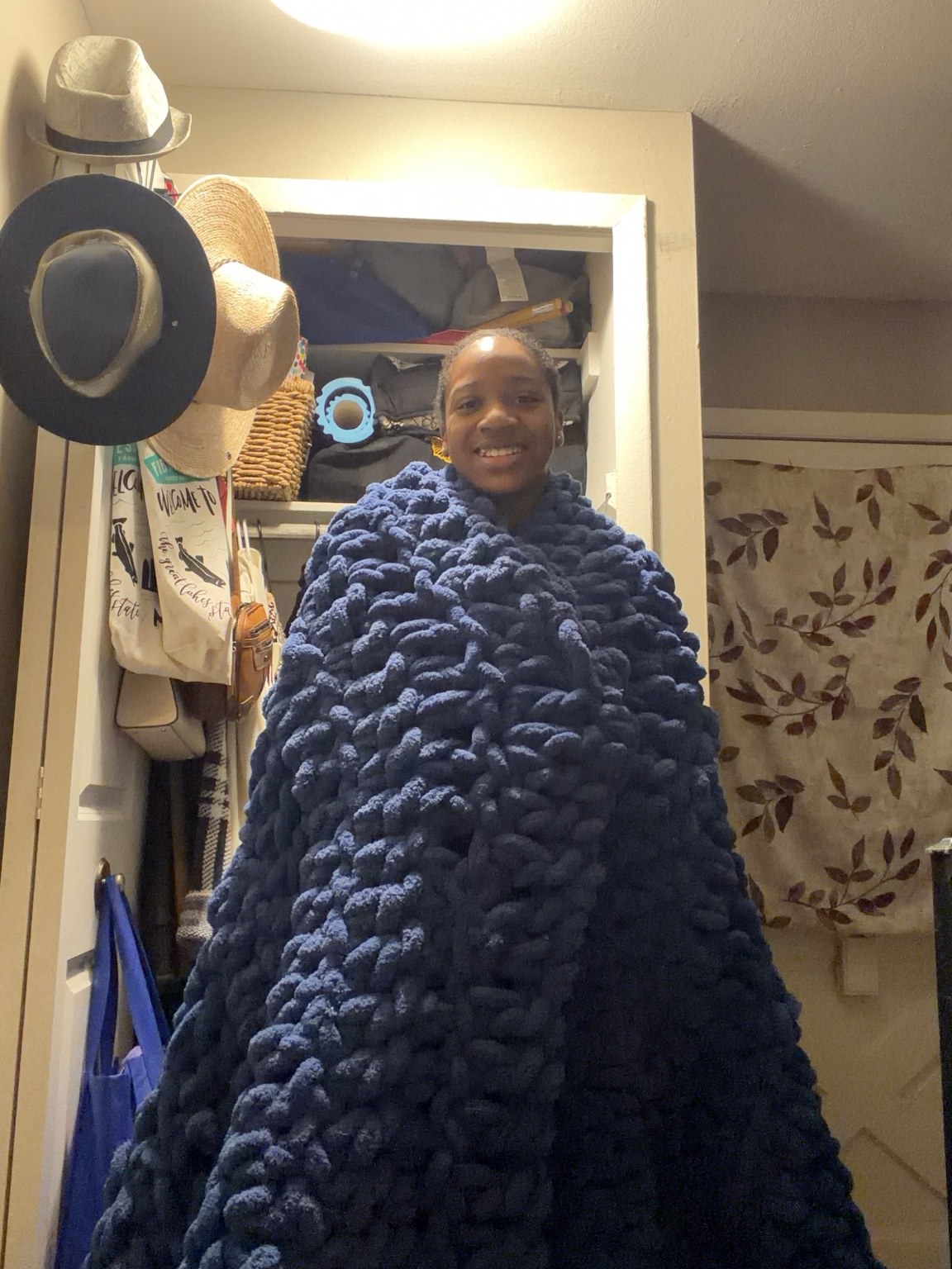 Natalea smiling, wrapped in her handmade navy blanket